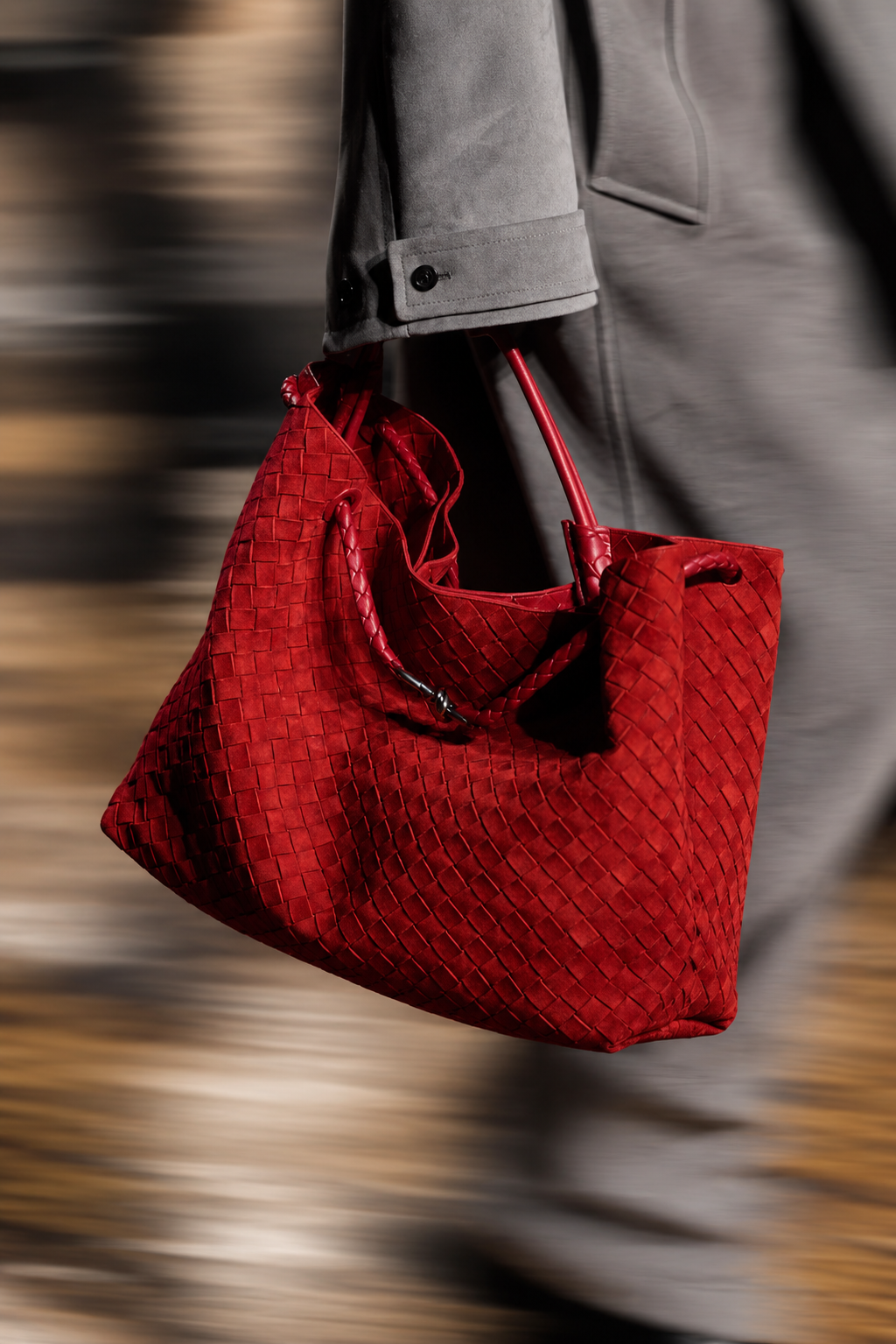 Red woven suede tote carried through strong horizontal motion blur