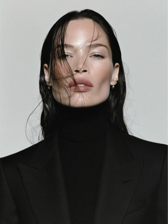 Portrait of a woman in a black tailored coat, hair across the face