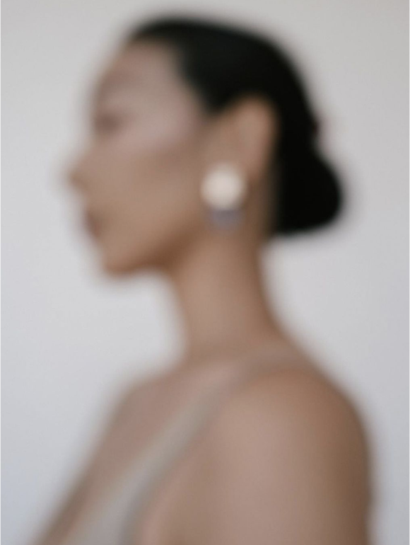Blurred profile of a woman wearing a single pearl earring