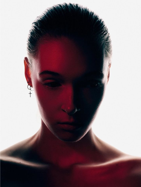 Portrait of a woman in deep red light, hair lifted across the frame