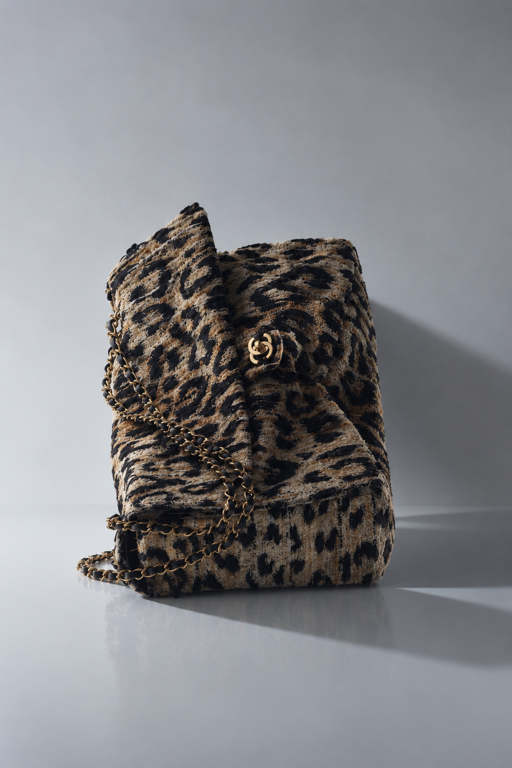 Leopard-pattern tweed flap bag with chain strap in directional studio light