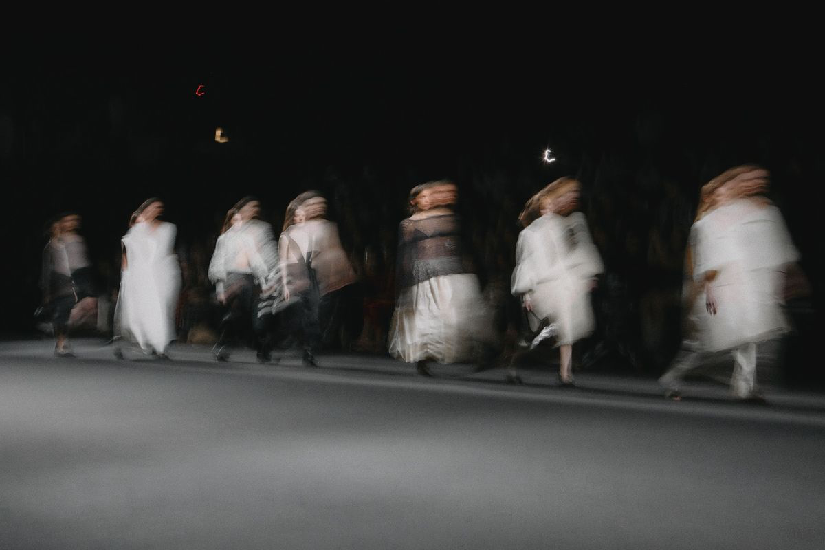 Figures in white crossing a darkened runway